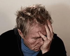 man holding face in hand because he lost his house